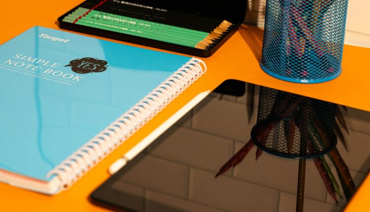 A desk with a laptop, notebook, and a cup of pencils