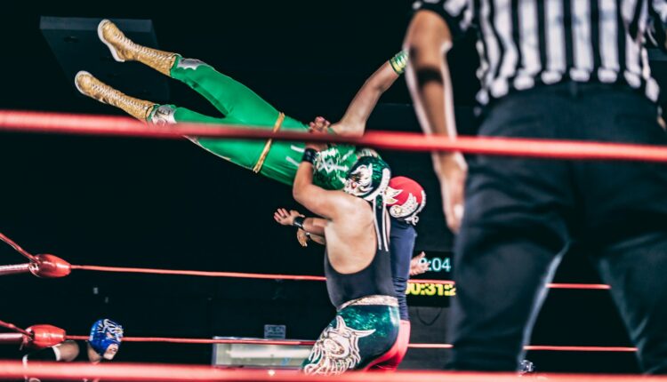 a person holding another man in a ring with a crowd watching