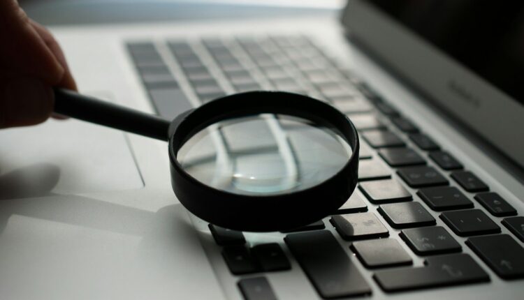 magnifying glass near gray laptop computer