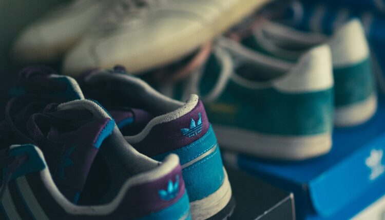 a row of adidas shoes sitting on top of a blue shelf